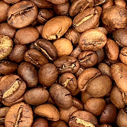 A close-up pile of roasted coffee beans in shades of medium to dark brown with lighter tan highlights.
