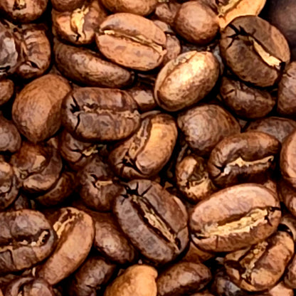 A close-up, top-down view of roasted coffee beans filling the entire frame, showing their rich dark brown color and characteristic crevices.