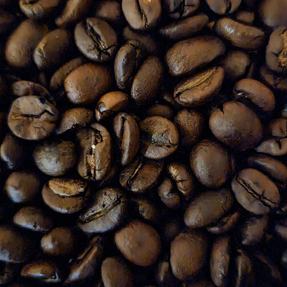 A close-up, top-down view of roasted coffee beans filling the frame, showing their glossy dark brown surfaces and characteristic creases.