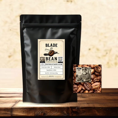 A black stand-up coffee bag labeled Blade & Bean Post Roast Coffee Roasted sits on a wooden surface against a textured beige wall, with a small square coffee bean pack placed beside it.