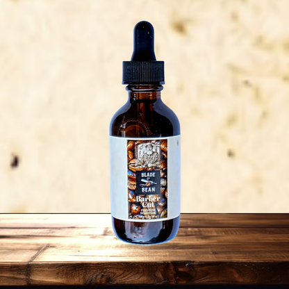 An amber glass dropper bottle with a black cap and a white label reading 'Blade Bean Barber Cut' and 'Hair Fx', standing on a wooden surface against a textured beige background.