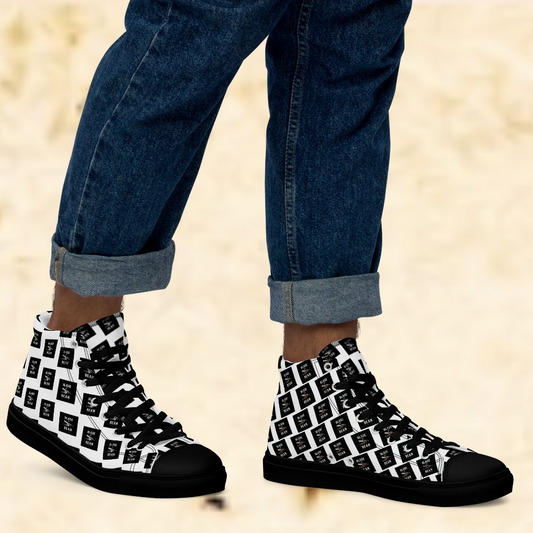 Black high-top sneakers with white pattern worn with rolled-up jeans on a beige background