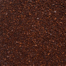 A close-up texture shot of dark brown coffee grounds or a fine granular powder filling the entire frame.