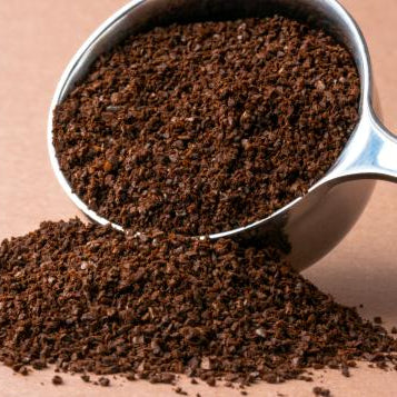 Close-up of coarse coffee grounds for cold brew coffee with a metal scoop on a brown background