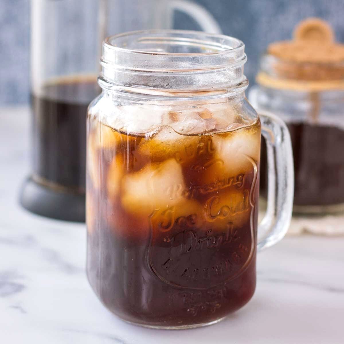 Mason jar filled with iced coffee on a marble surface