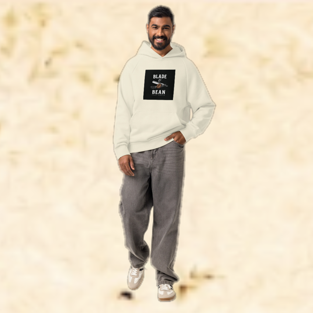 Man wearing a light gray hoodie with a logo and text, standing against a beige background