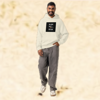 Man wearing a light gray hoodie with a logo and text, standing against a beige background