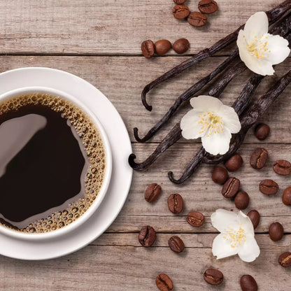 Cup of coffee with vanilla beans and flowers on a wooden surface