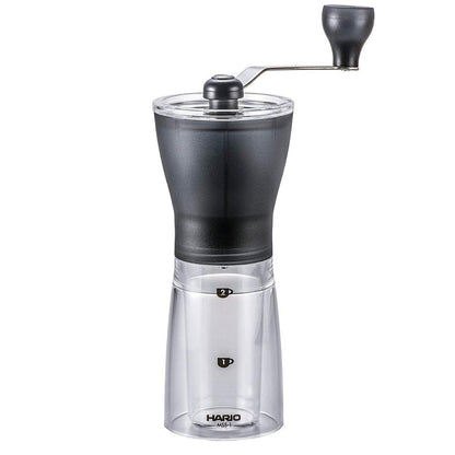 Hario Mini Slim+ hand coffee grinder with clear and black design on a white background