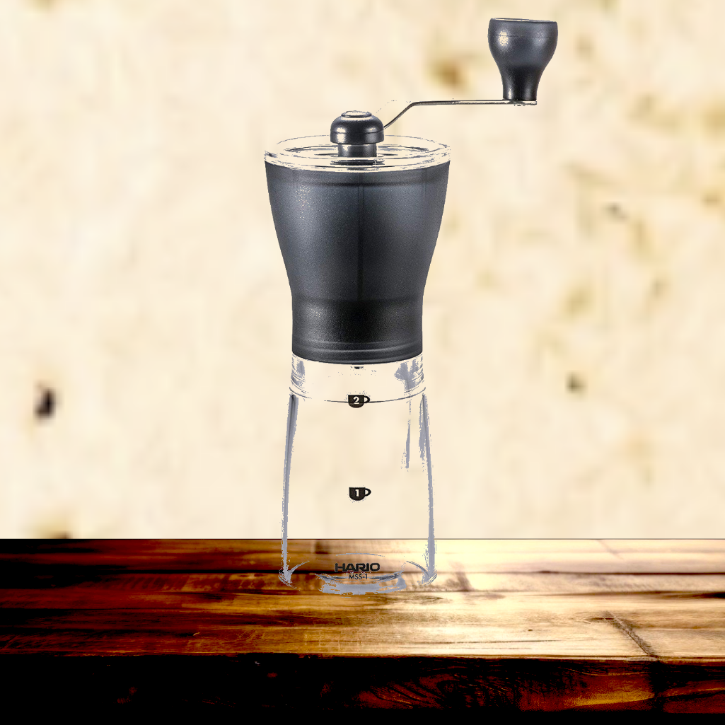 Black manual coffee grinder on a wooden surface with a blurred background