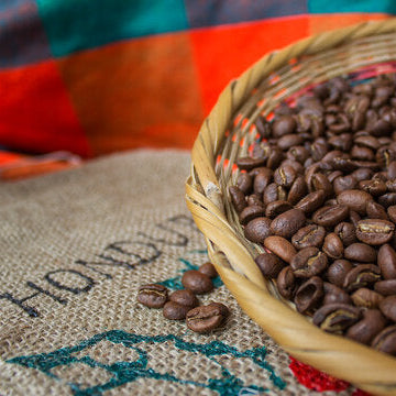 Basket of coffee beans on a Honduras coffee bag with colorful fabric in the background