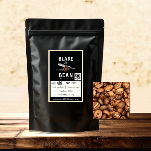 A black stand-up coffee pouch labeled Blade & Bean Roastery Max Caf with a small inset photo of roasted coffee beans, displayed on a wooden surface against a warm beige textured background.