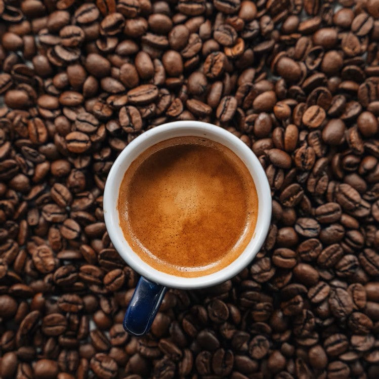 Espresso cup filled with coffee on a bed of Cowboy Cut coffee beans from Blade & Bean