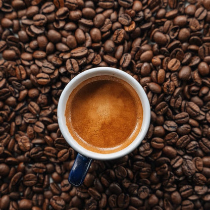 Espresso cup filled with coffee on a bed of Cowboy Cut coffee beans from Blade & Bean