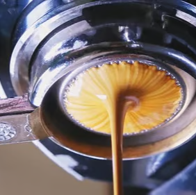 Close-up of coffee being extracted with an espresso machine.