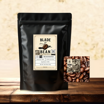 A black stand-up coffee bag labeled Blade & Bean The coffee sits on a wooden surface with a small square coffee bean graphic card beside it against a textured beige wall.