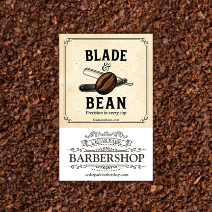 A rectangular barbershop sign or label centered over a background of dark brown coffee beans. The top section is cream with black text reading 'BLADE & BEAN' and a coffee blade graphic; the bottom section is white with 'CEDAR PARK BARBERSHOP' and website text.