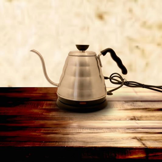 Stainless steel gooseneck kettle on a wooden surface with a blurred background